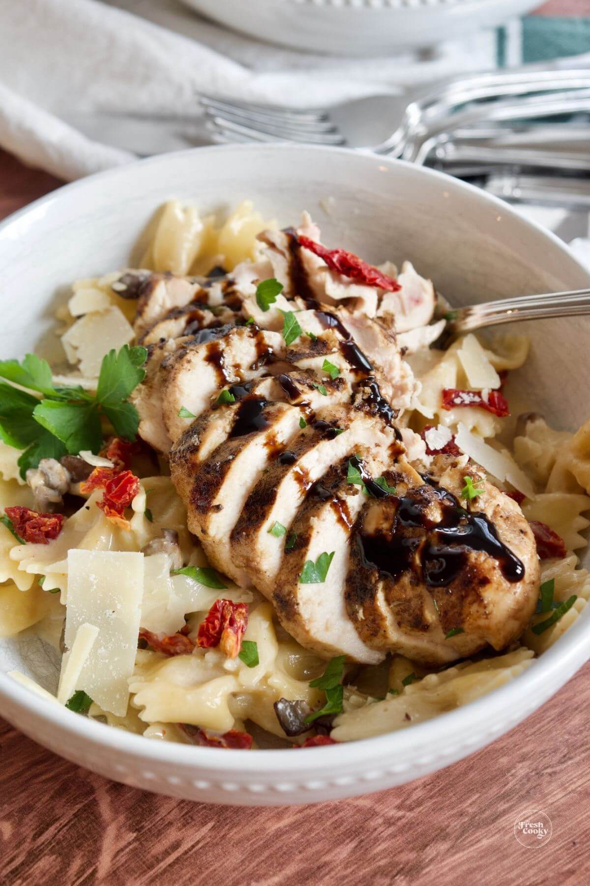Chicken farfalle in bowl drizzled with balsamic glaze.