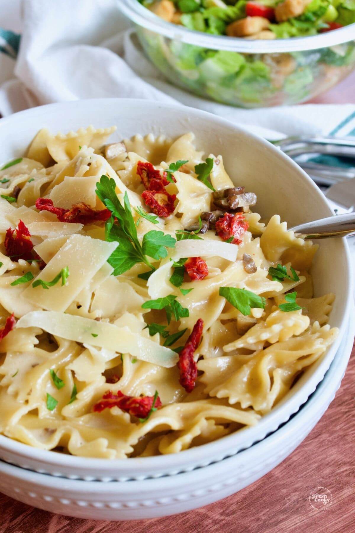 Pasta bowls filled with al dente bow tie pasta in light cream sauce with sun-dried tomatoes and mushrooms.
