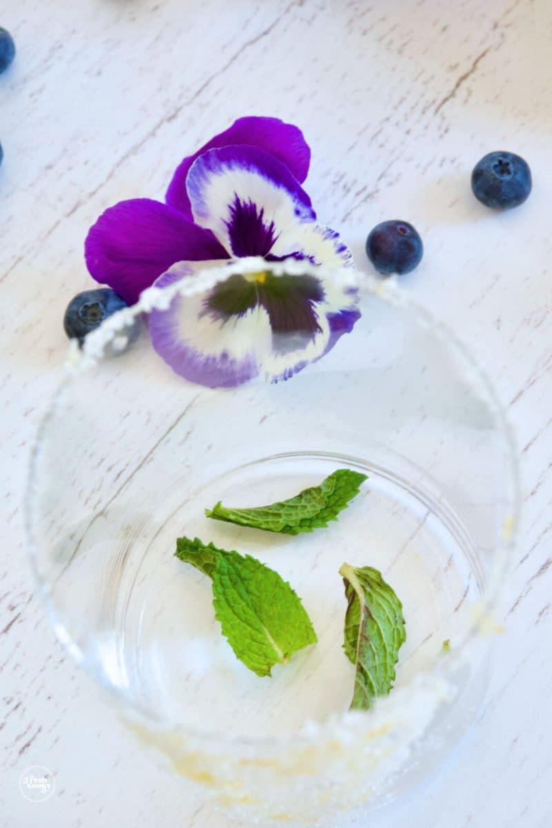 Add mint leaves to sugared glass and muddle.