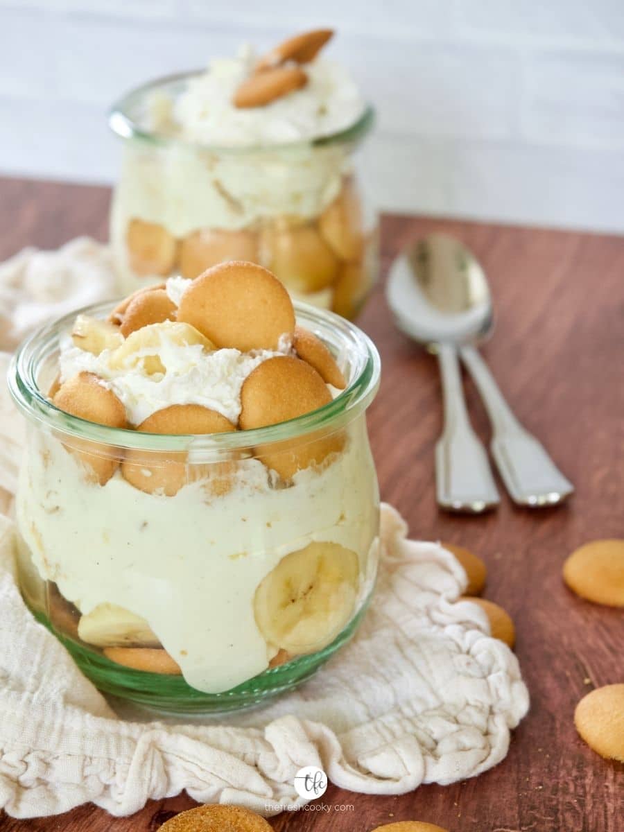 A small jar filled with Magnolia Banana Pudding with another behind with two spoons.