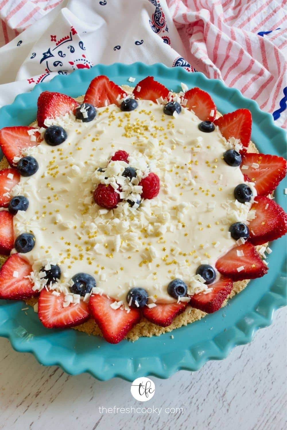 Patriotic Lemon Cream Pie decorated with sliced strawberries and blueberries and shaved chocolate with edible gold stars.