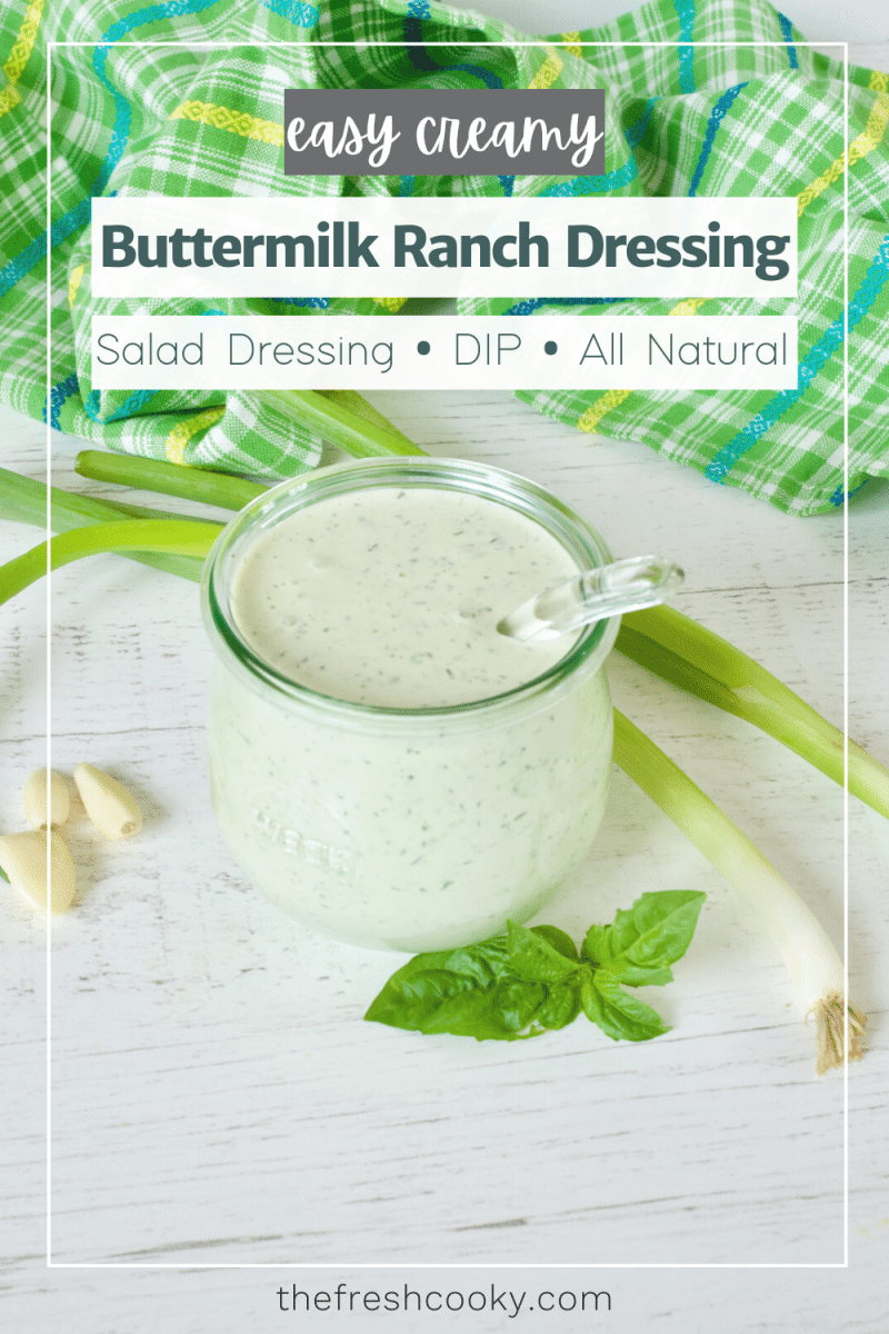Buttermilk Ranch Dressing pin with image of glass jar of ranch dressing sitting on a wooden table with green onions, fresh basil and garlic cloves laying around.