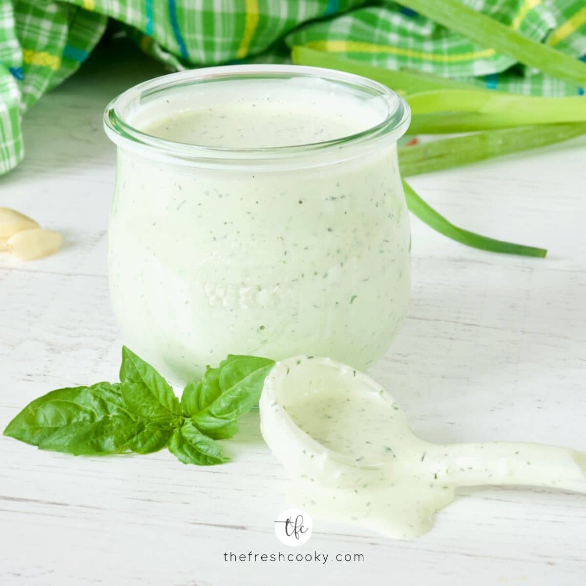 Buttermilk Ranch dressing in pretty shaped jar with fresh basil and a scoop pudding ranch dressing.