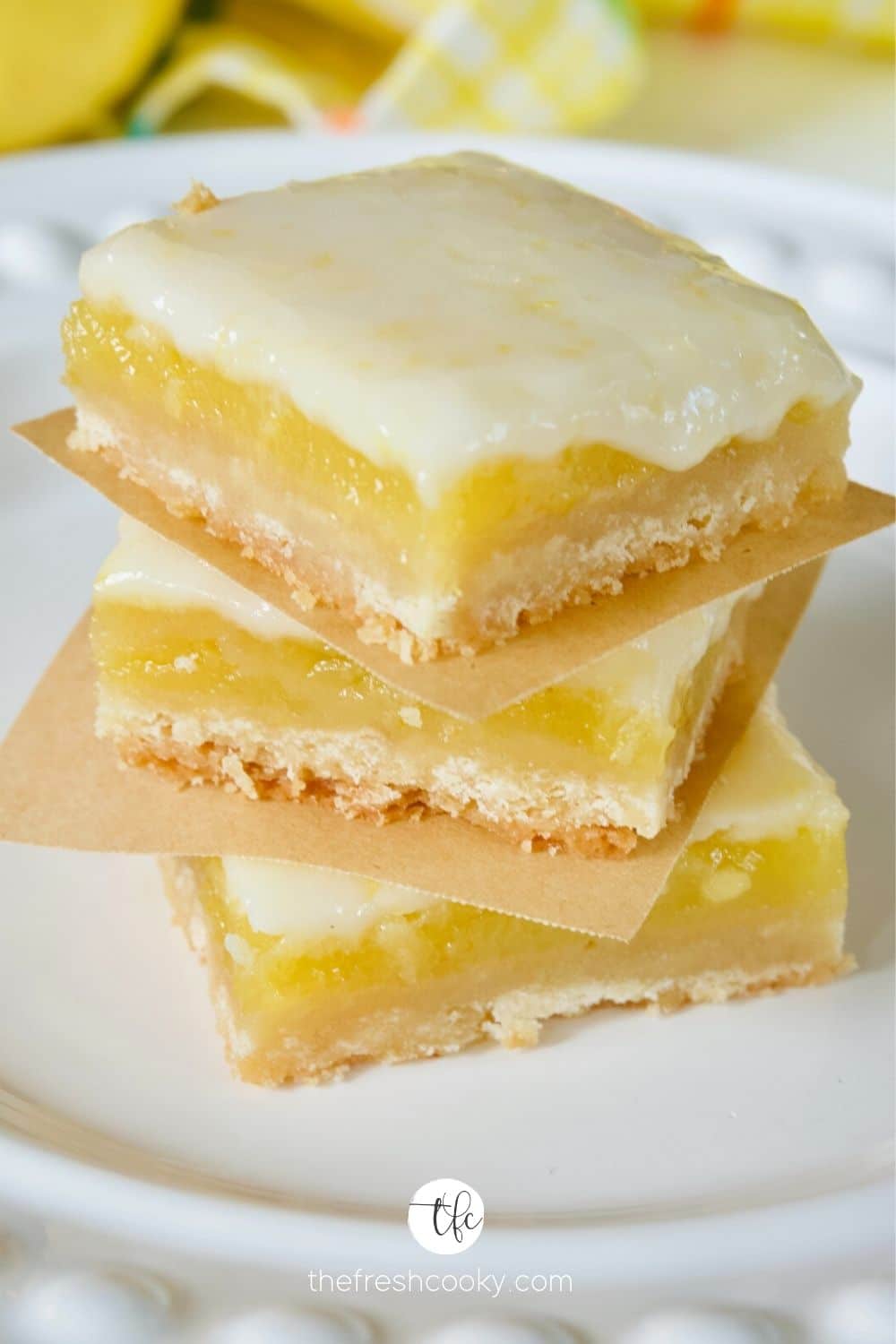 Clean sliced Old Fashioned Lemon Squares stacked on top of one another with parchment paper between.