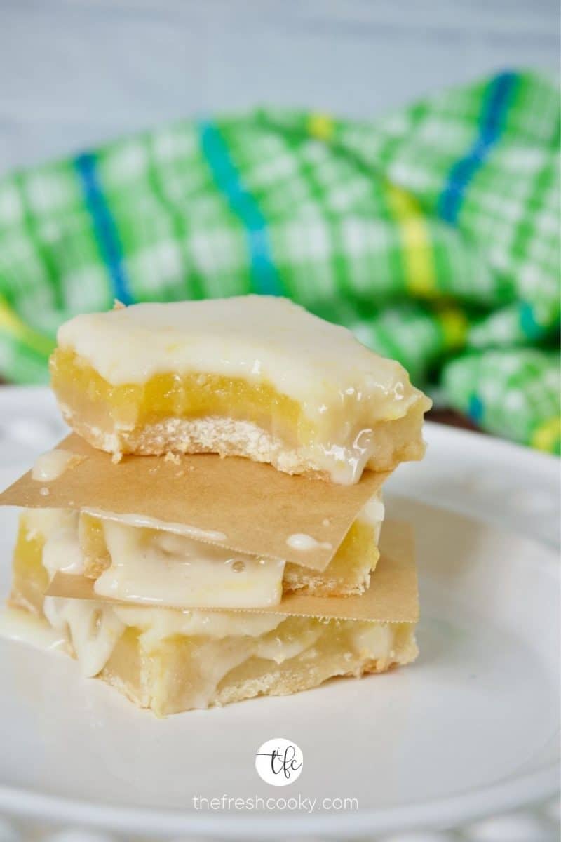Stack of gooey lemon squares with bite taken out of top square.