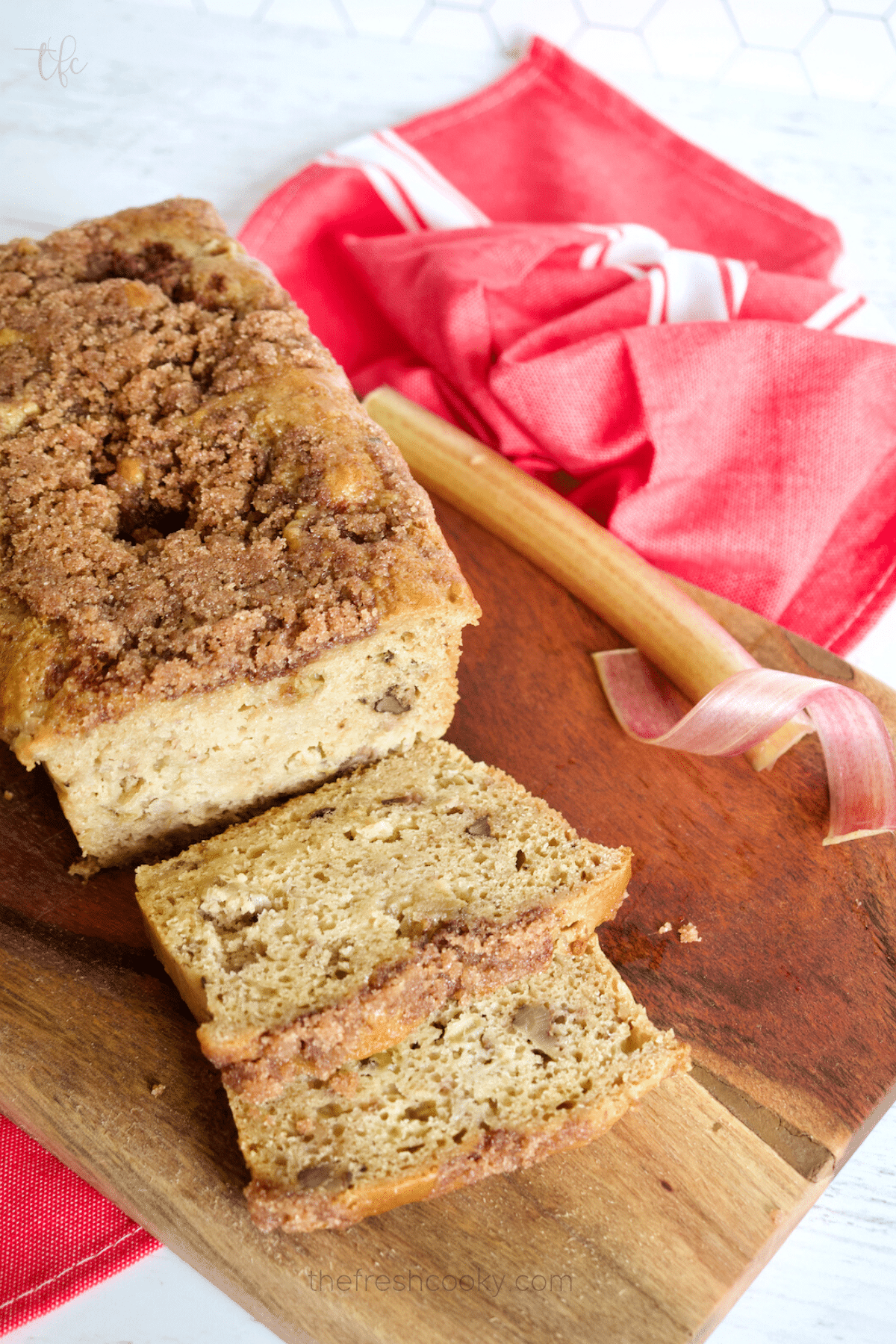 Easy buttermilk rhubarb bread on cutting board sliced with rhubarb ribbons in background.