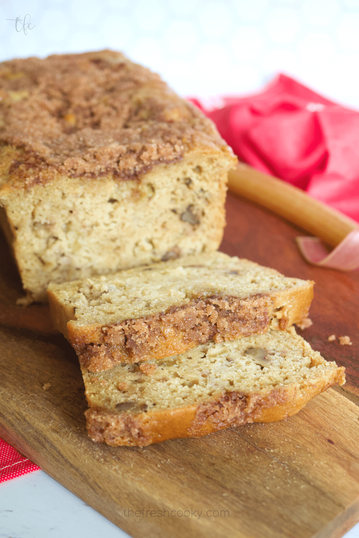 Sliced buttermilk rhubarb bread with stalk of red rhubarb behind the bread.