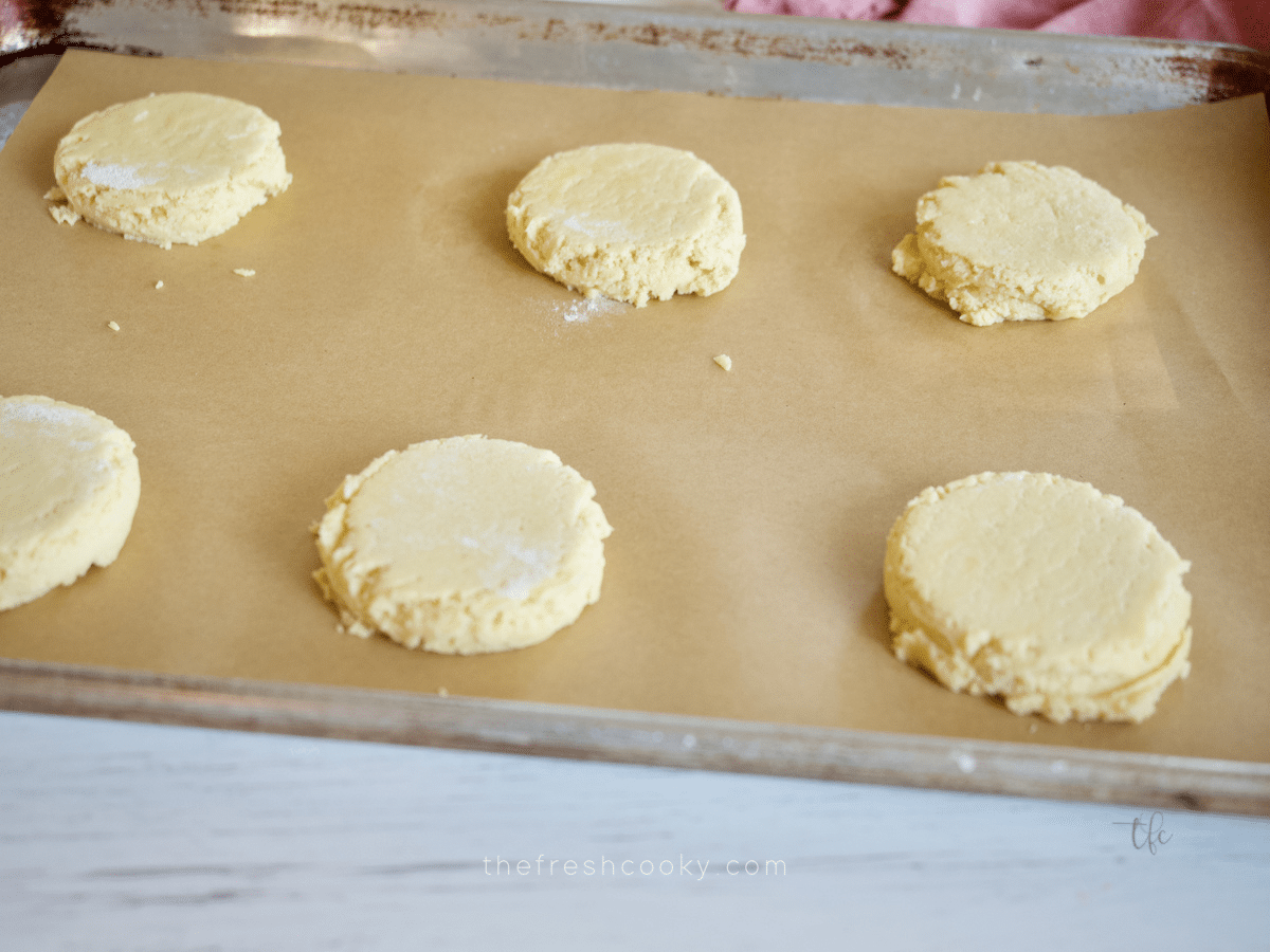 Flattened Crumbl Sugar Cookies on baking sheet ready for oven.