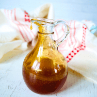 A cruet jar filled with dark sticky hot honey.
