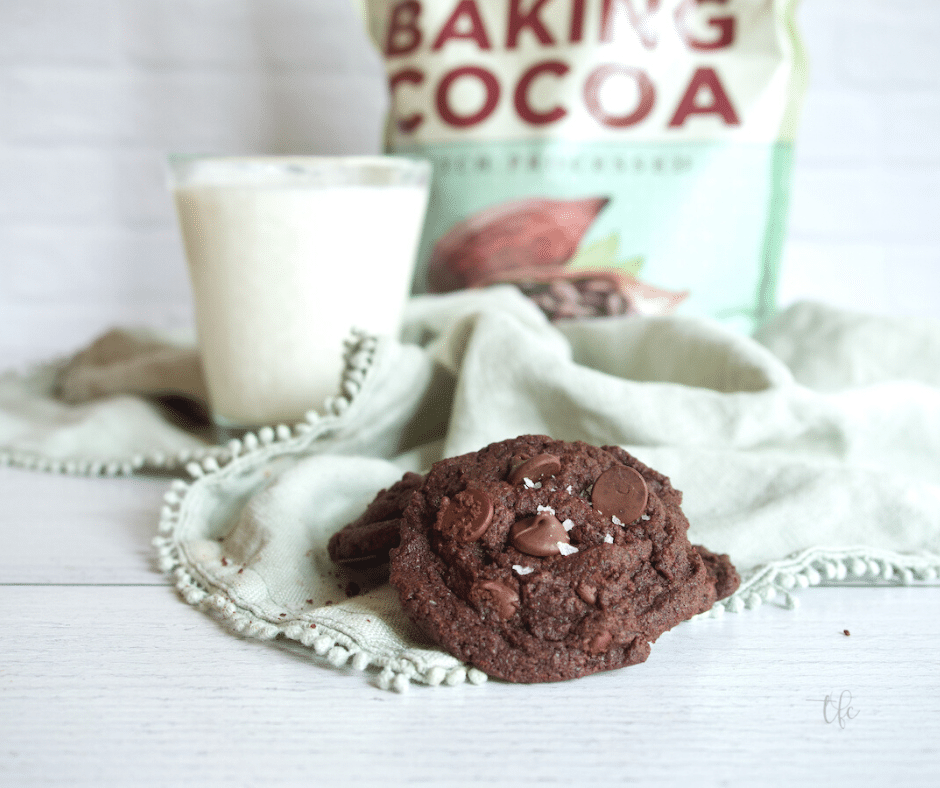 Triple Chocolate Cookies with glass of milk and bag of Rodelle Baking Cocoa in background.
