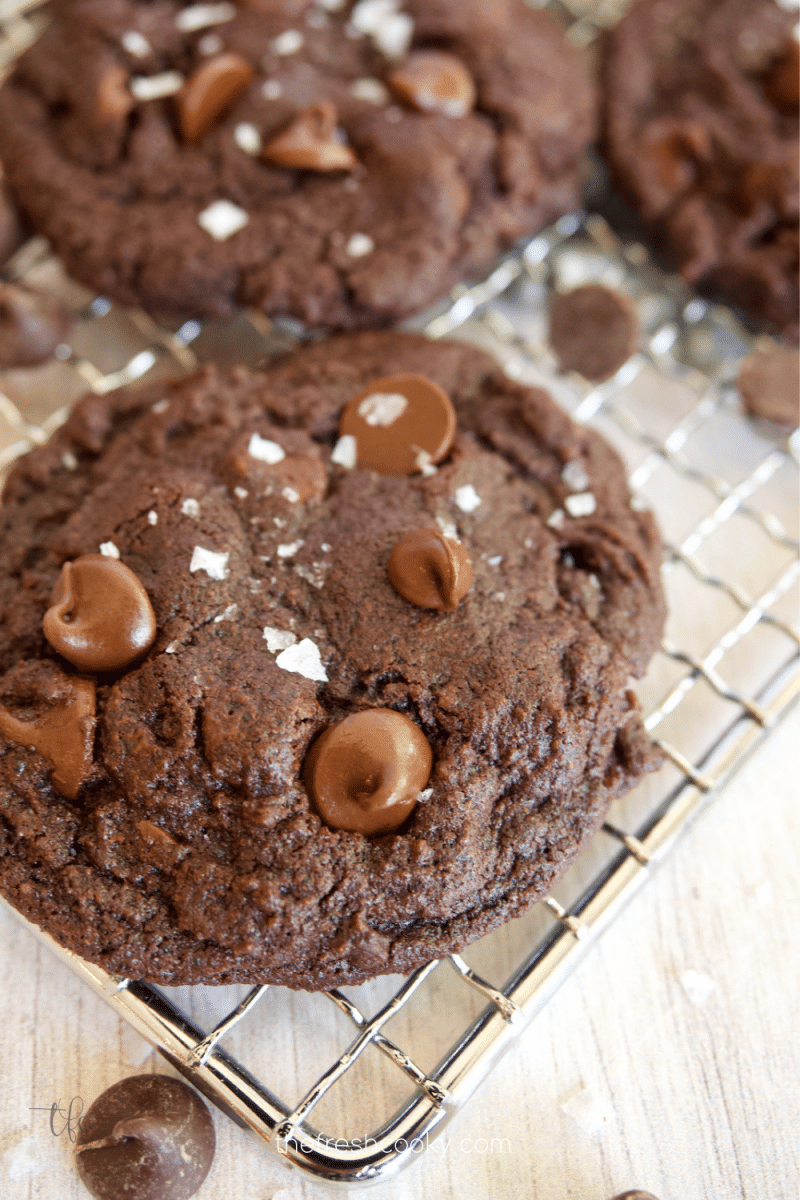 Triple Chocolate cookies with flaky sea salt on wire cooling rack.