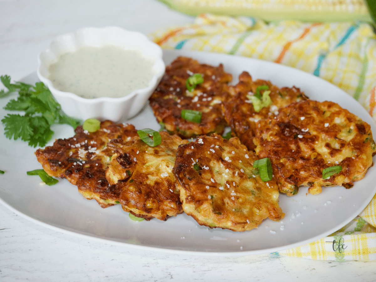 Facebook image of zucchini corn fritters on an oval plate with ranch dressing.