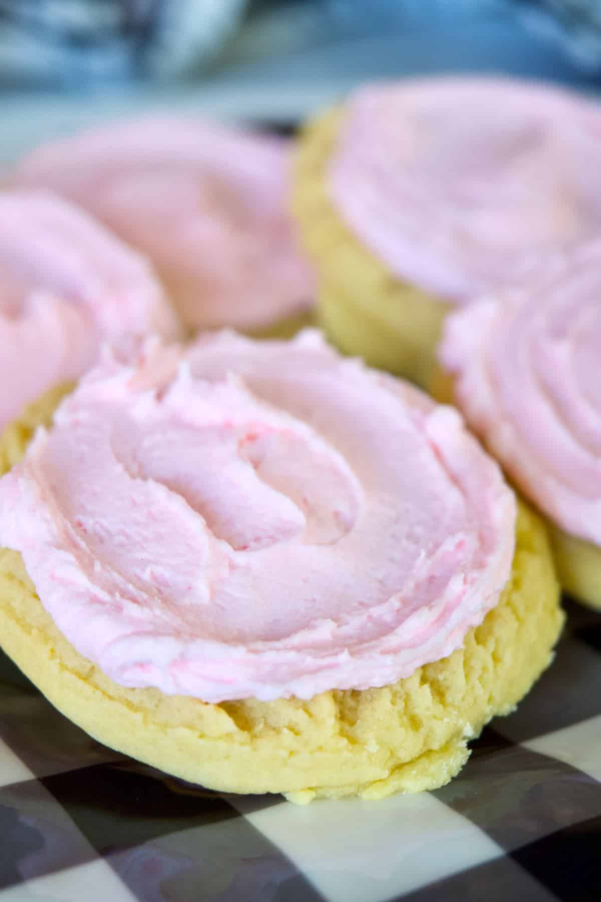 Close-up of giant crumbl sugar cookie with pink frosting swirled on top.