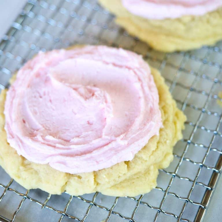 Chilled frosted Crumbl Sugar cookies on wire rack.