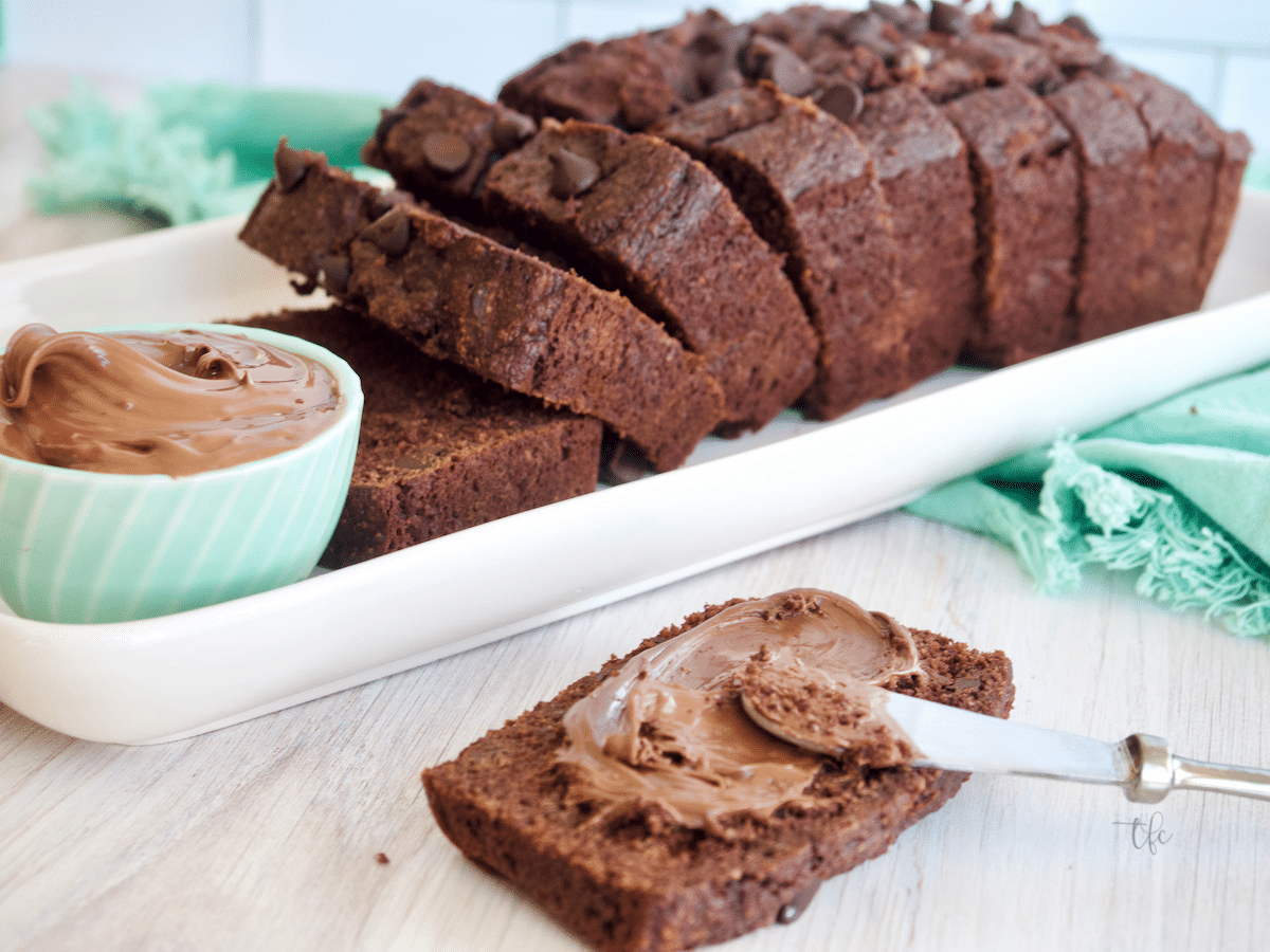 Healthy Chocolate Chip Banana Bread sliced on a platter with some nutella spread onto a slice.