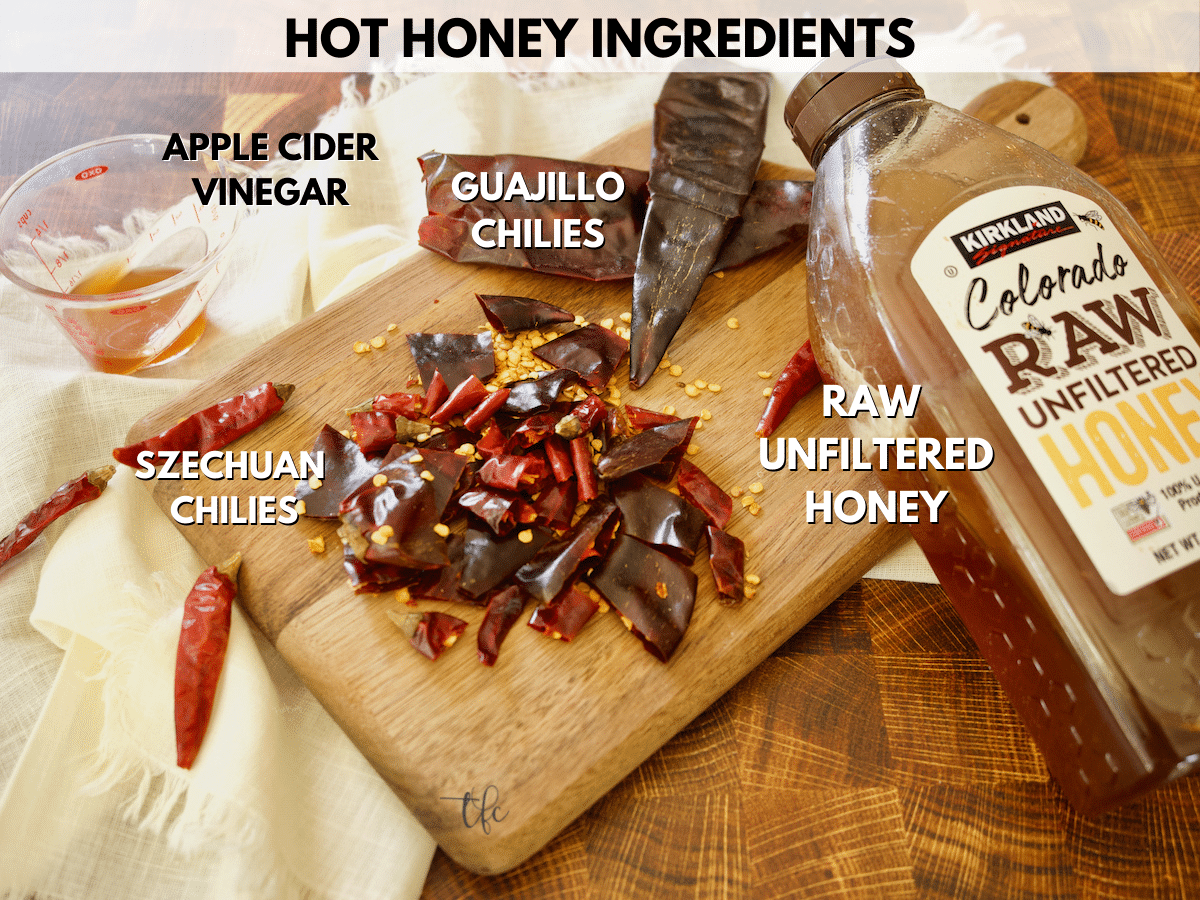 Ingredients for hot honey recipe with apple cider vinegar, chopped szechuan and guajillo chili peppers, and honey.