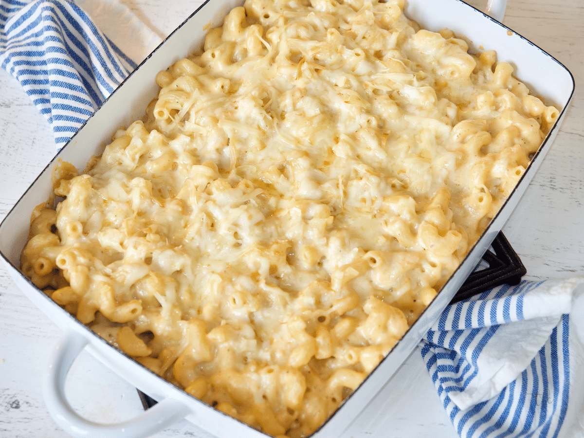 Creamy smoked mac and cheese in a casserole dish with a striped blue and white towel underneath.