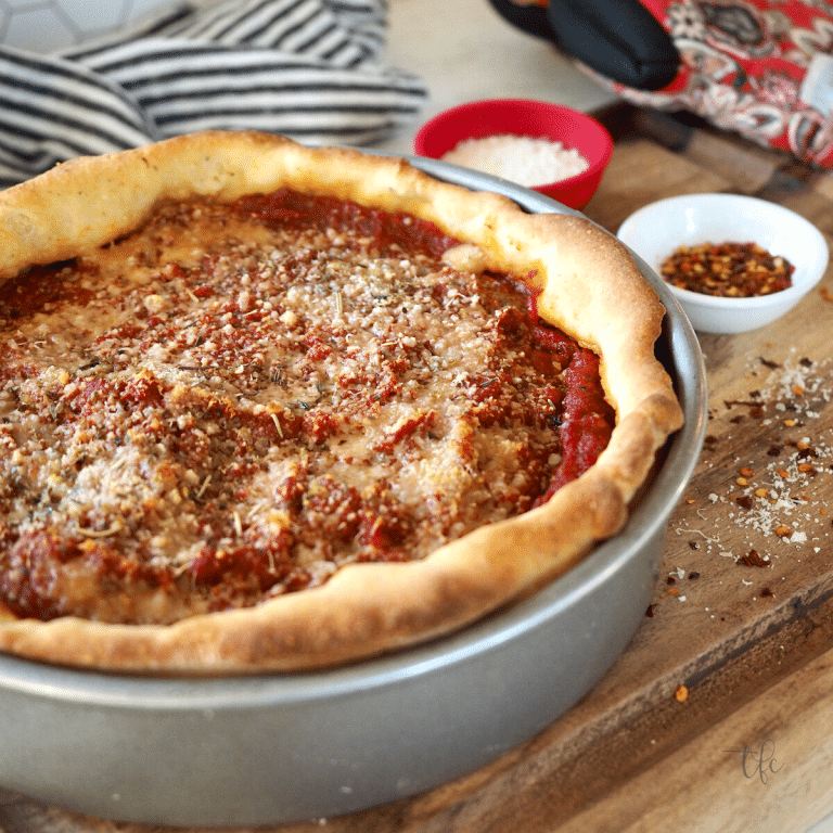 Chicago-Style Deep dish pizza in pan with condiments fresh out of the oven.