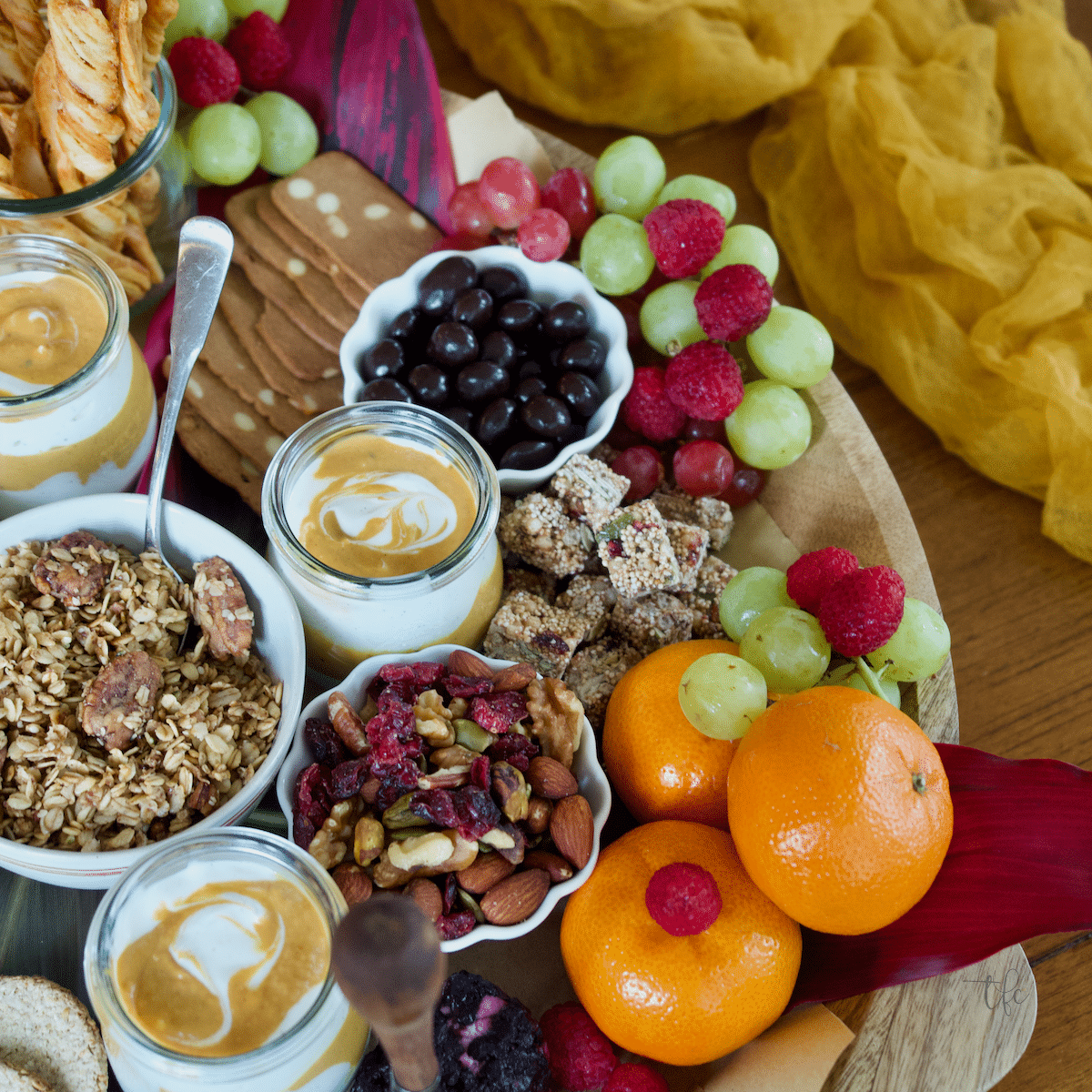 Fall Charcuterie Board with image of right half of board, highlighting the granola, oranges and fruit, trail mix and more. 