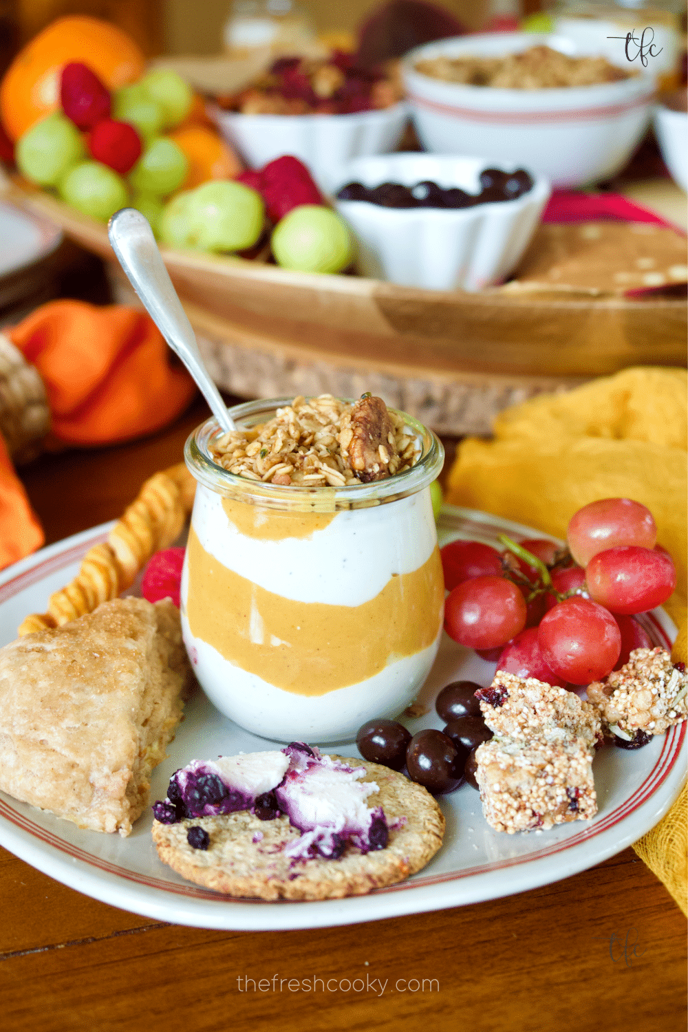 A plate filled with delicious pumpkin yogurt, cinnamon scones, cheese and crackers, grapes and other nibbles from the fall charcuterie breakfast board.
