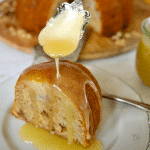 slice of Pear bundt cake recipe with a spoon drizzling vanilla sauce on top.