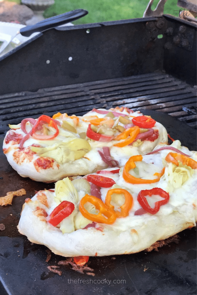 How to bake homemade pizza in the oven and on the grill, with image of two pizzas on the grill. 