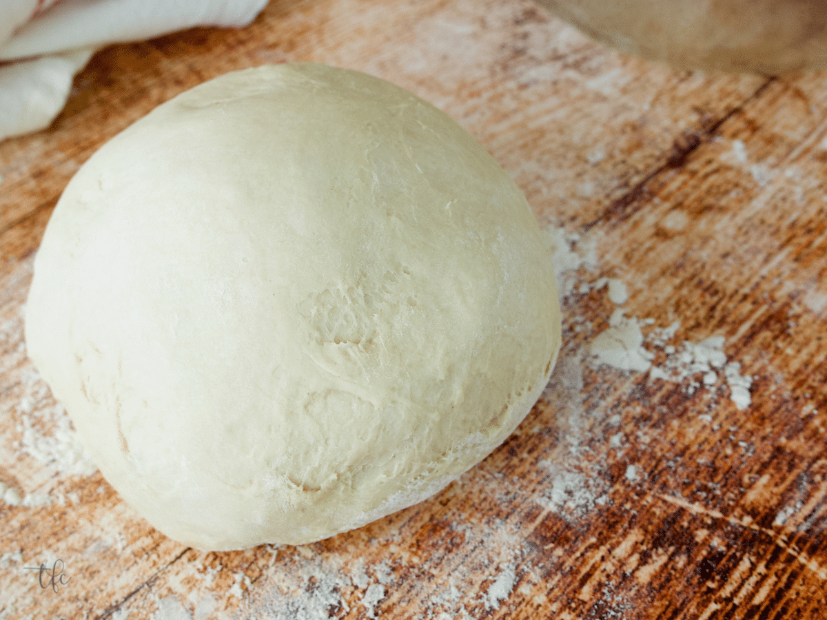 Pizza dough ready for storing on floured table.