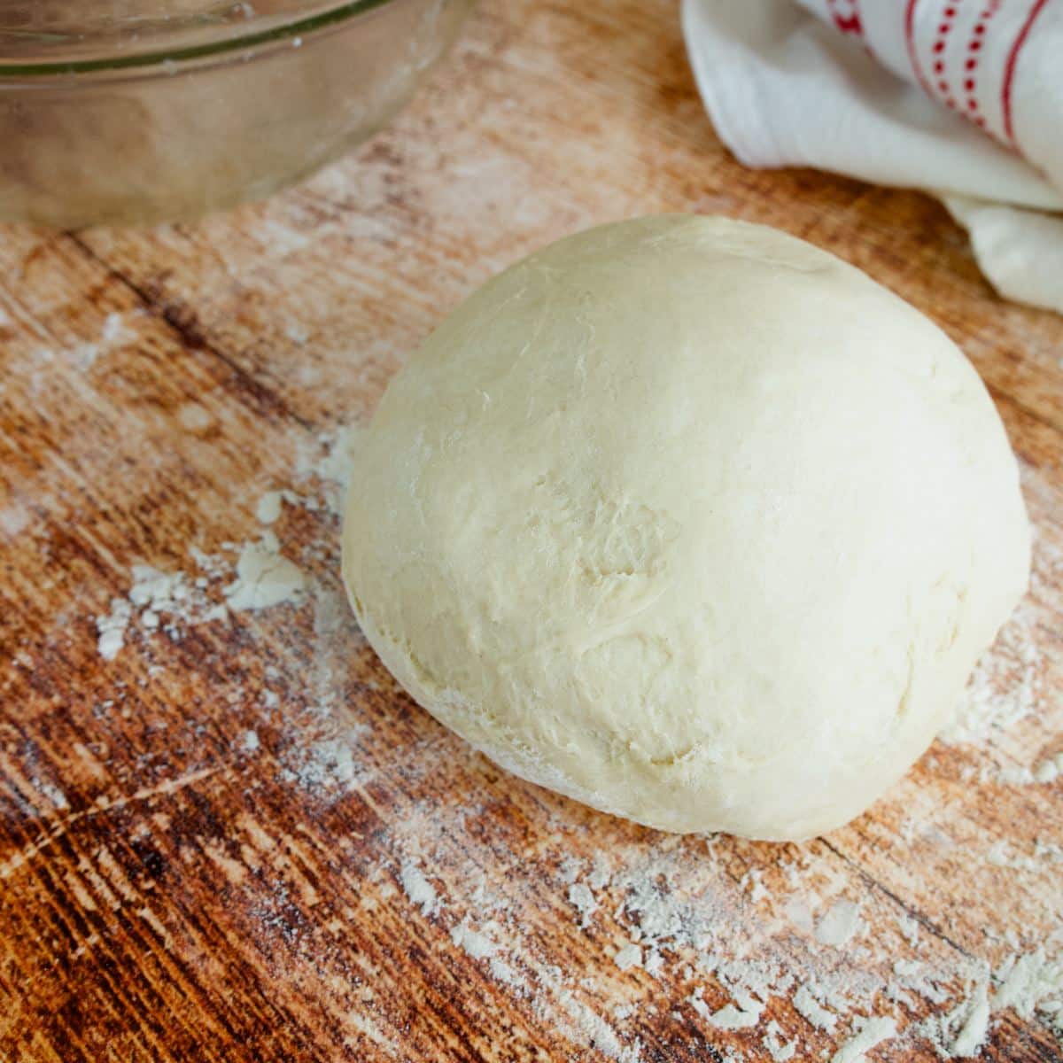 A ball of pizza dough on a floured surface. 