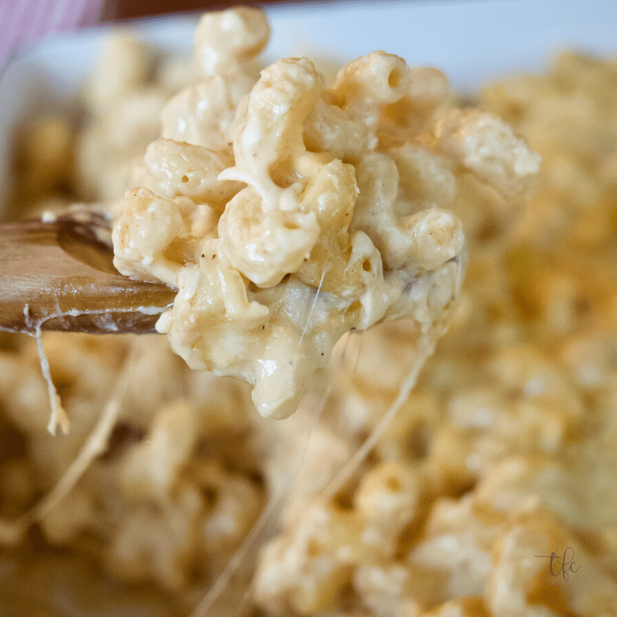 Smoked Mac and Cheese Gooey and cheesy smoked cheese sauce smothering macaroni noodles in pan with spoon pulling up serving.