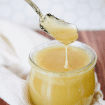Vanilla Sauce in pretty glass jar with silver spoon drizzling sauce with a dripping.