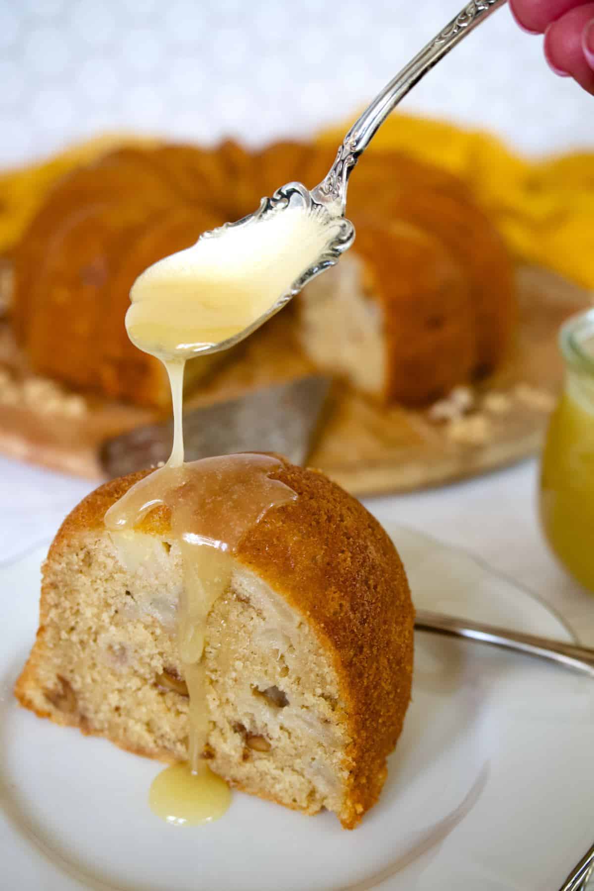 Vanilla sauce being spooned onto pear bundt cake.