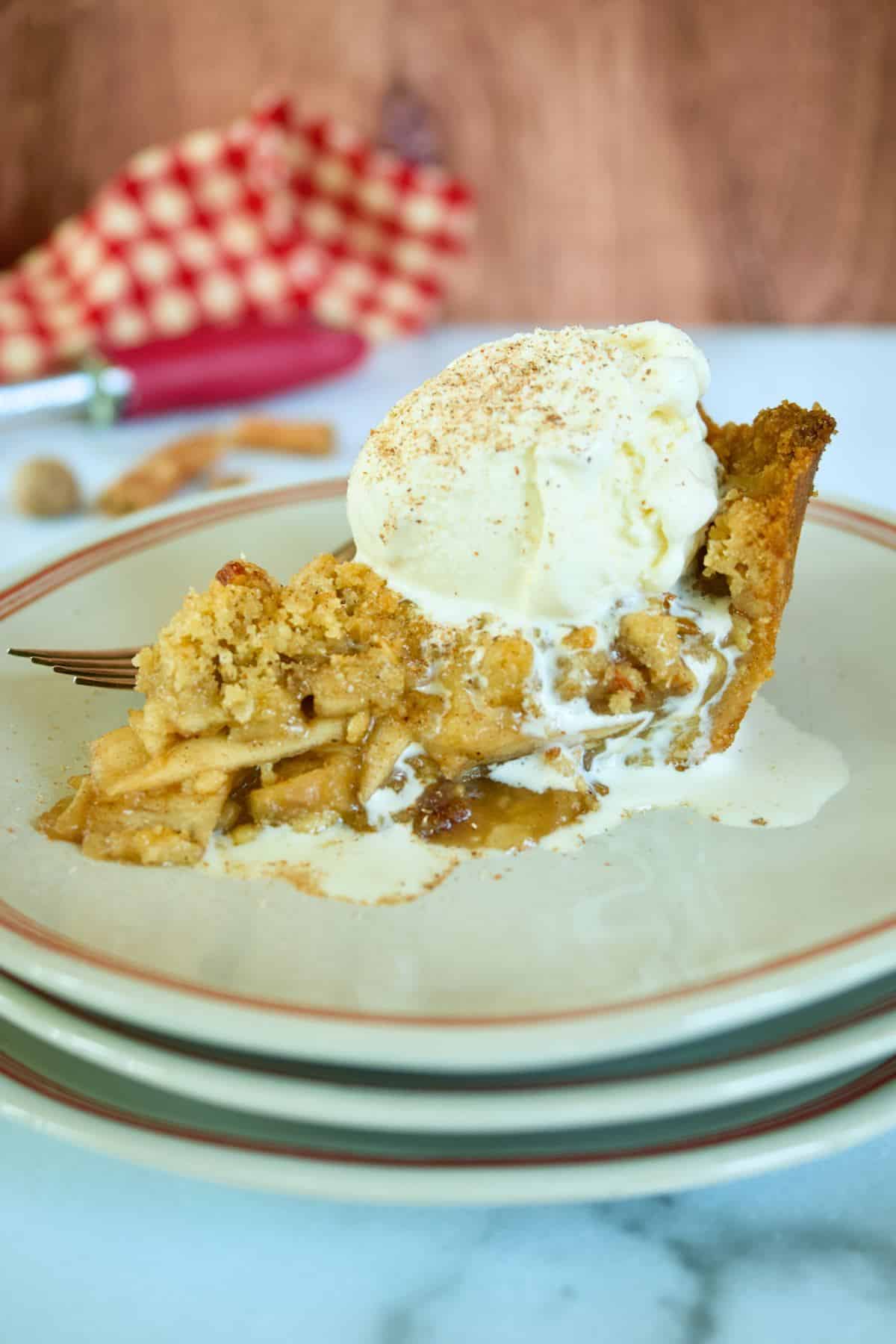 Slice of gluten free apple pie topped with vanilla ice cream.