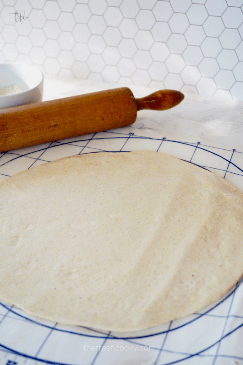 After second rise, rolled out deep dish pizza dough with rolling pin behind. 