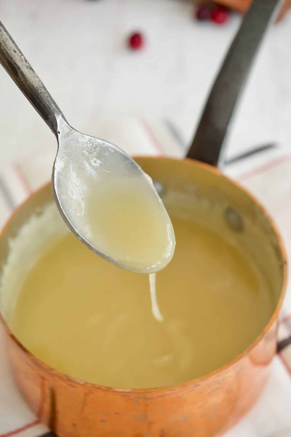 A spoon in pan filled with thick butter sauce.
