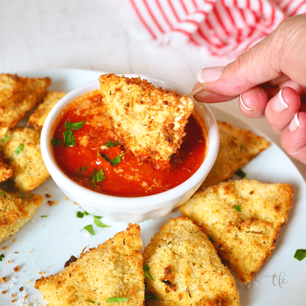 Air Fryer Toasted Ravioli with hand dipping in marinara sauce.