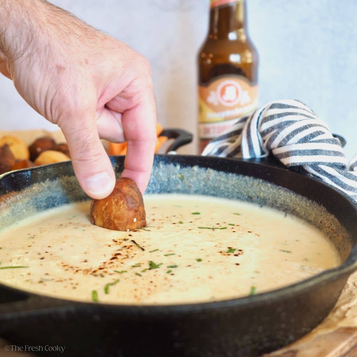 Hand dipping pretzel bite into beer cheese dip.