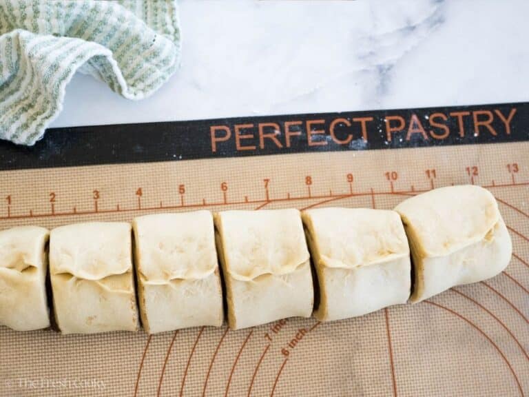 Cinnamon roll dough sliced into rolls on pastry silpat.