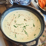 Easy beer cheese pretzel dip in cast iron skillet with pretzel bites and carrots for dipping.