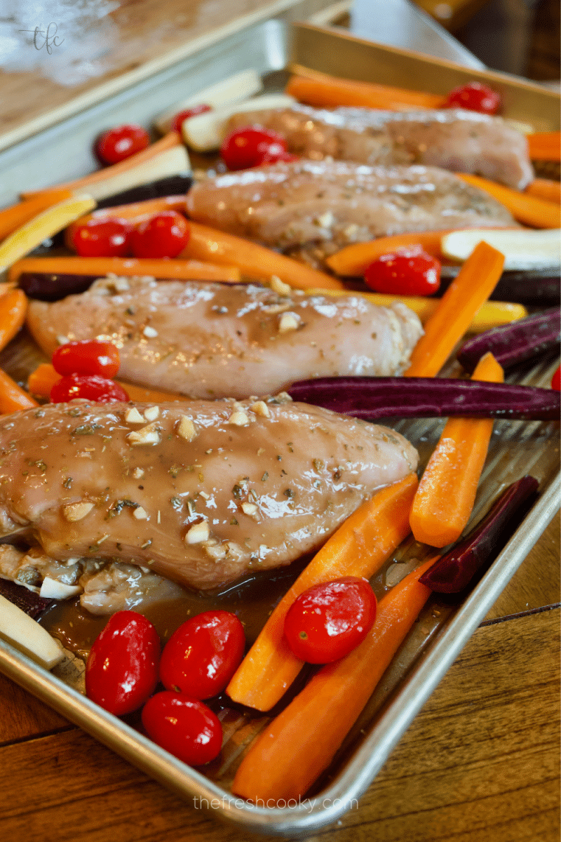 Nestle marinated balsamic chicken between the tomatoes, carrots and sun-dried tomatoes on a sheet pan. 