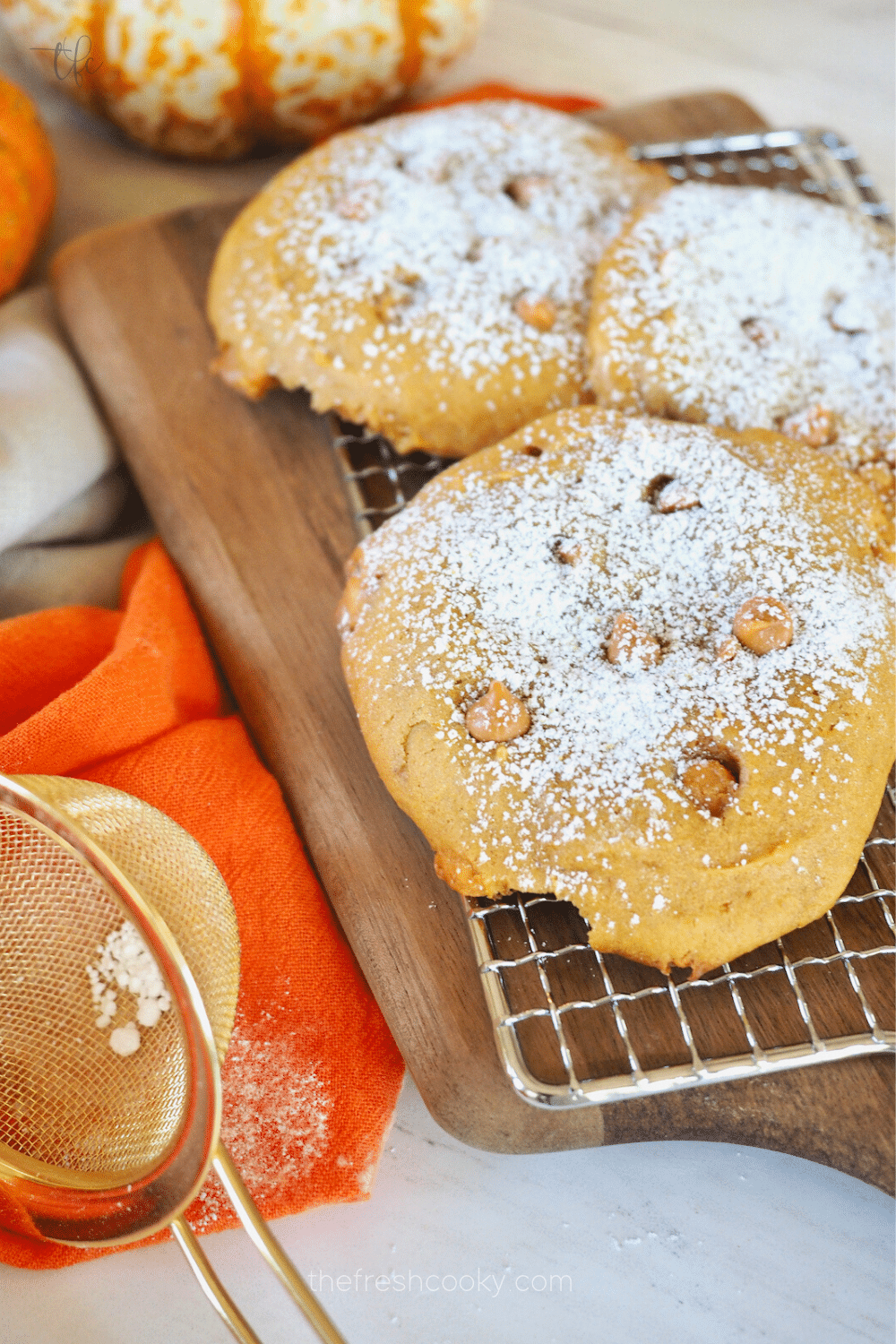 Giant Soft Pumpkin Cookies dusted with powdered sugar on wire rack.