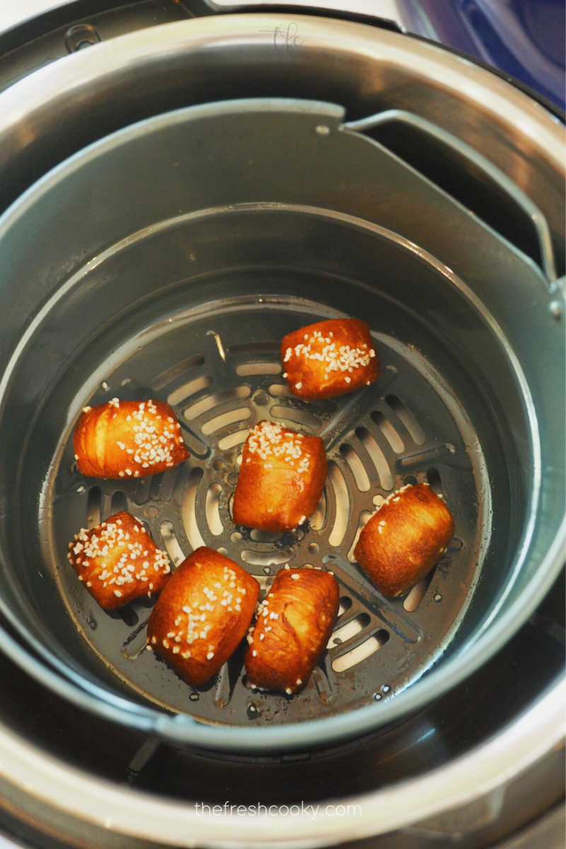 Puffed, dark brown and baked air fryer pretzel bites in air fryer basket. 