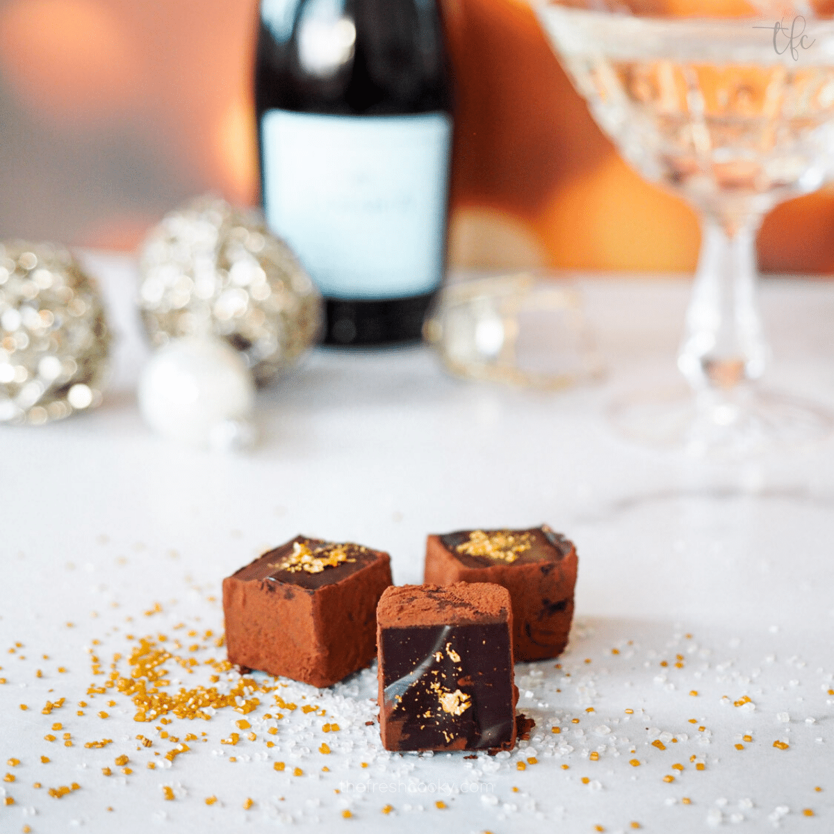 Champagne Truffles covered in a little gold leaf, with champagne bottle in the background, crystal glass and ornaments.