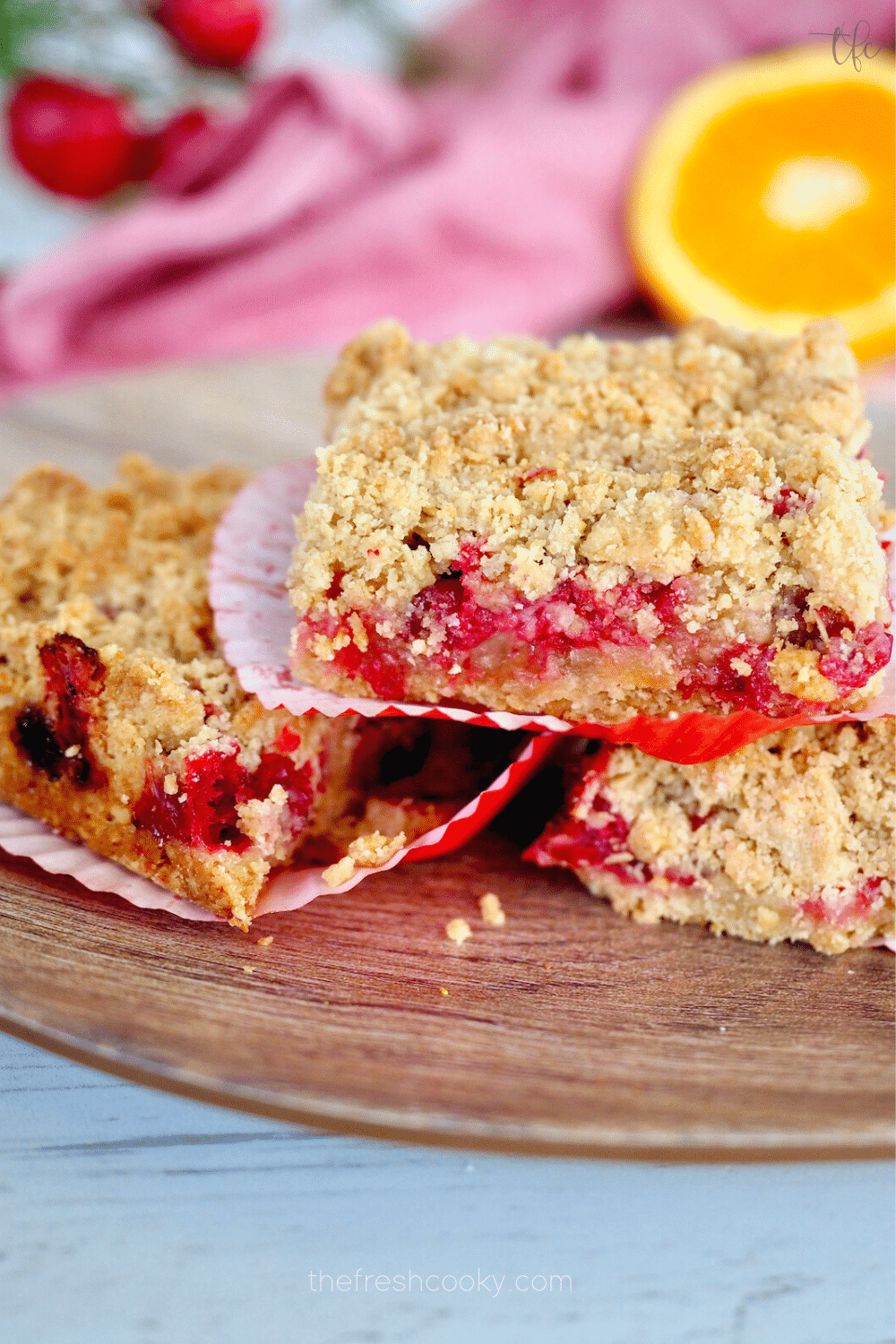 Oatmeal Cranberry Crumb Bars sliced into squares on a plate with an orange in the background.