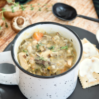 Creamy Instant Pot Chicken and Wild Rice Soup square image, with mug of thick, rich, steaming wild rice soup on a plate with saltine crackers.