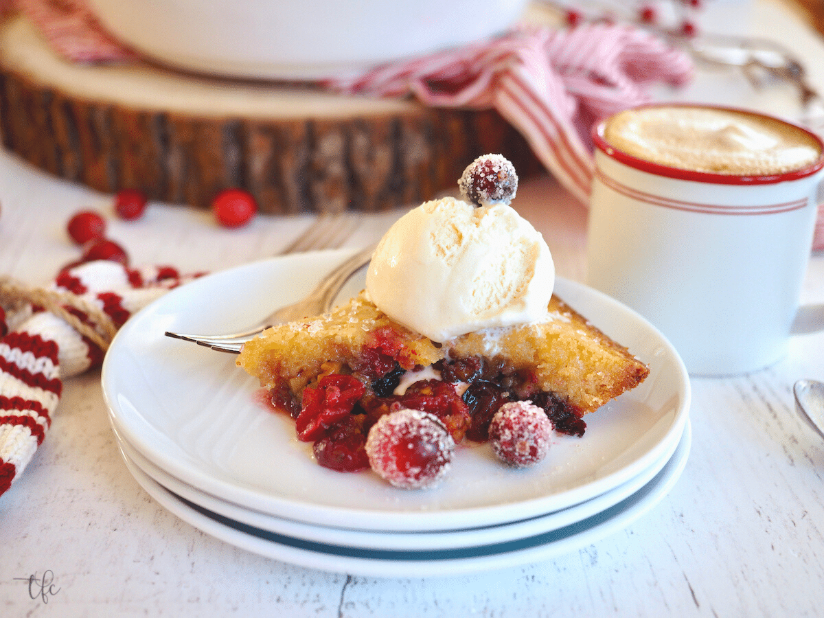 Slice of Nantucket Cranberry Pie on a plate with ice cream and sugared cranberries.