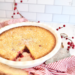 Nantucket Cranberry Pie whole in pretty white scalloped pie plate with slice removed revealing juicy cranberries.
