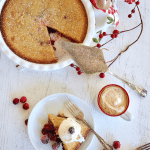 Nantucket Cranberry Pie with whole pie with one slice removed, slice on plate, with ice cream and sugared cranberries, cup of coffee nearby.