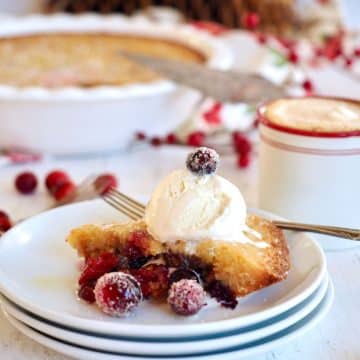 Slice of Nantucket cranberry pie on plate topped with vanilla ice cream and sugared cranberries.