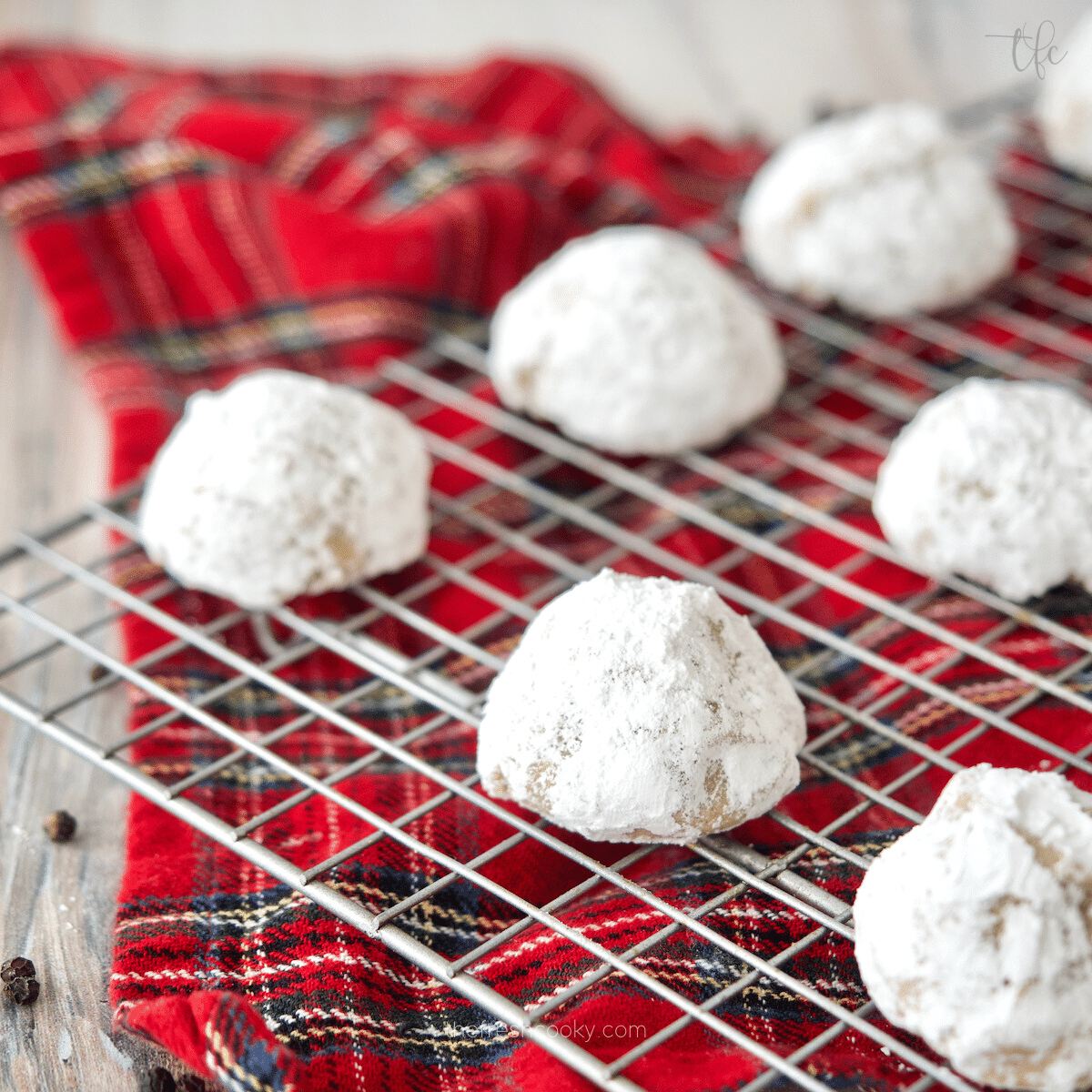 Pfeffernusse Cookies a German spice cookie on a cooling rack with a pretty red plaid towel underneath.