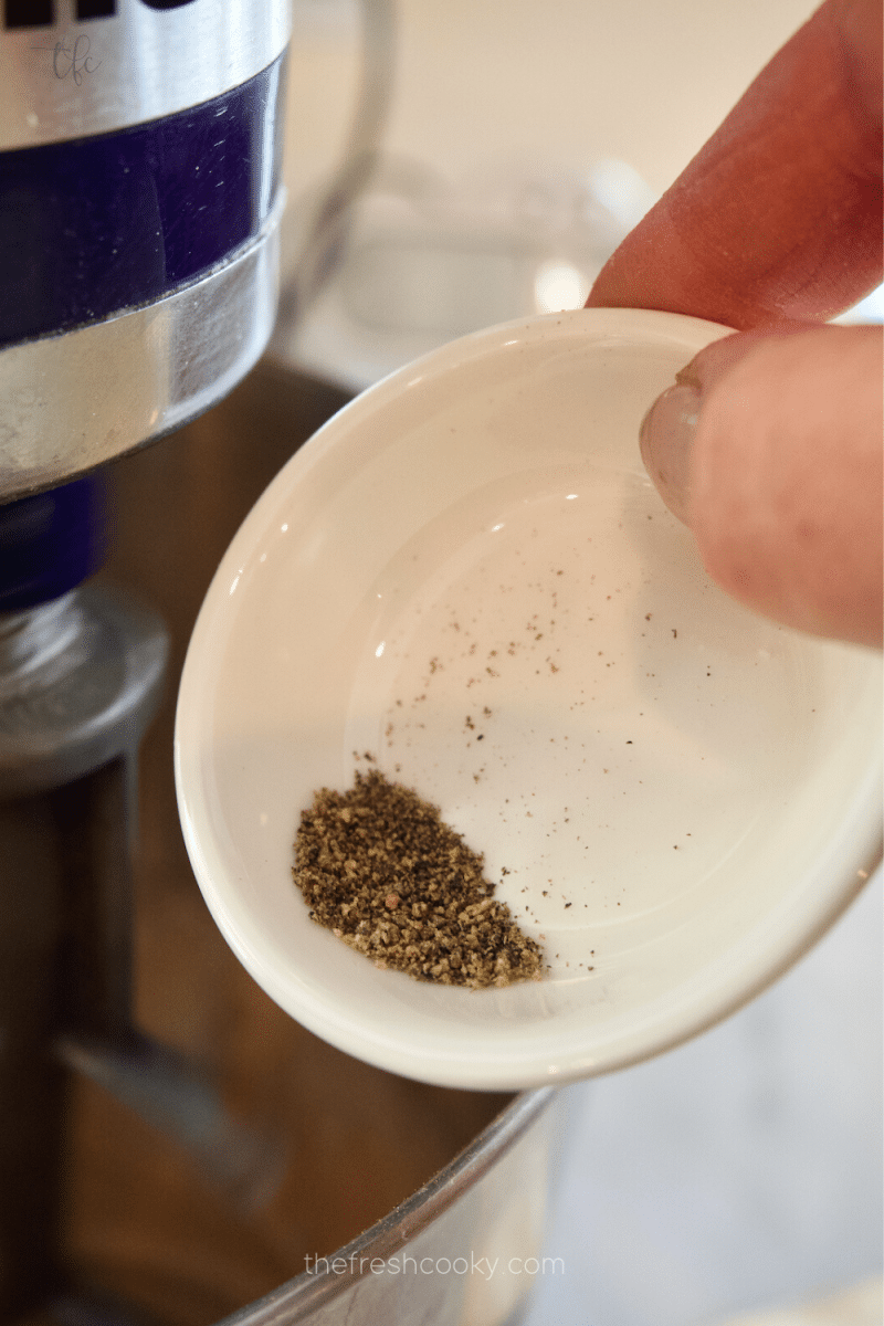 Adding black pepper to pfeffernusse cookie mixture.